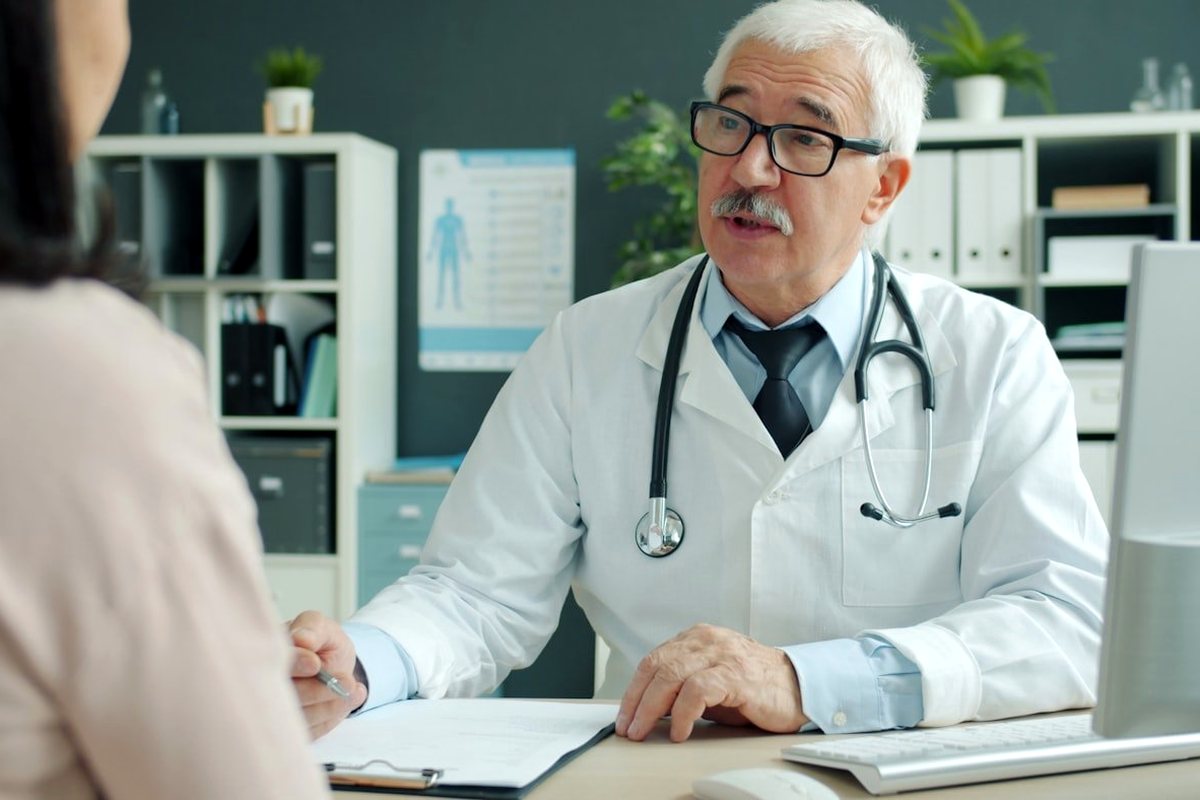 A doctor leaning in to talk with a patient during a consultation