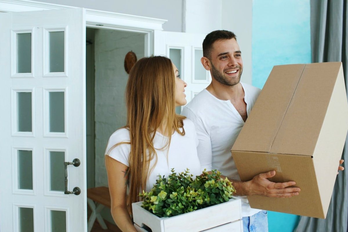 A couple carrying moving boxes into their new home
